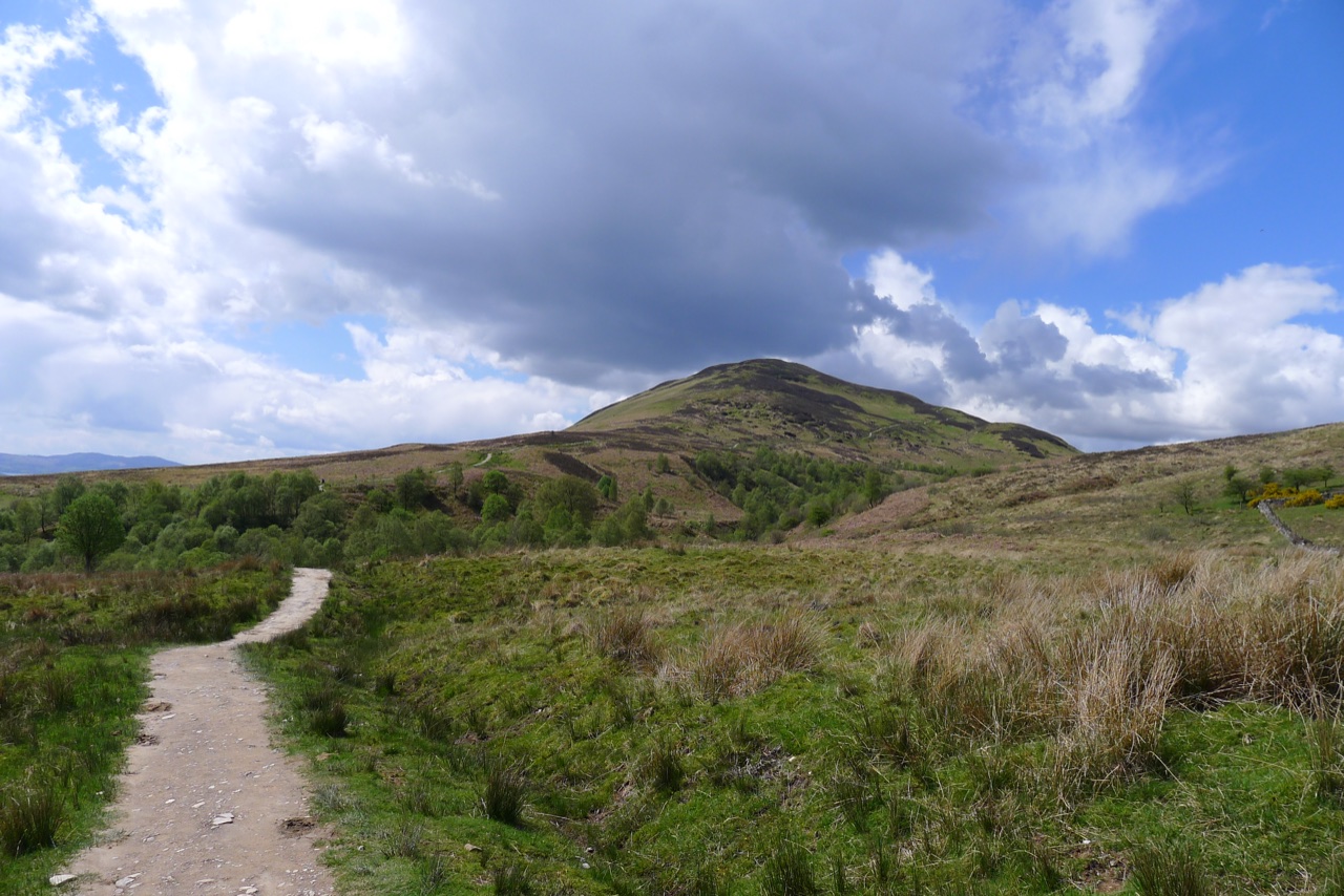 Path approaching Conic Hill under a changeable sky—arrival context for the walk from Balmaha.