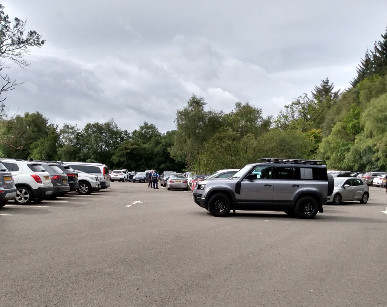 Visitor car park at Balmaha among woodland, with Conic Hill’s wooded slopes rising beyond.
