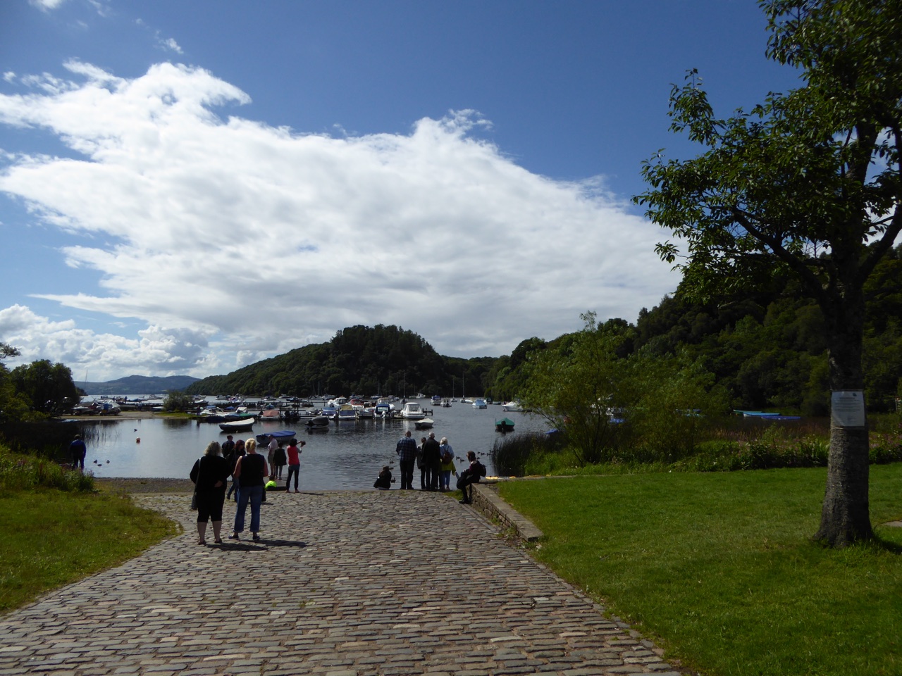 Balmaha piers and harbour on Loch Lomond with boats and wooded hills—lochside context after a walk.