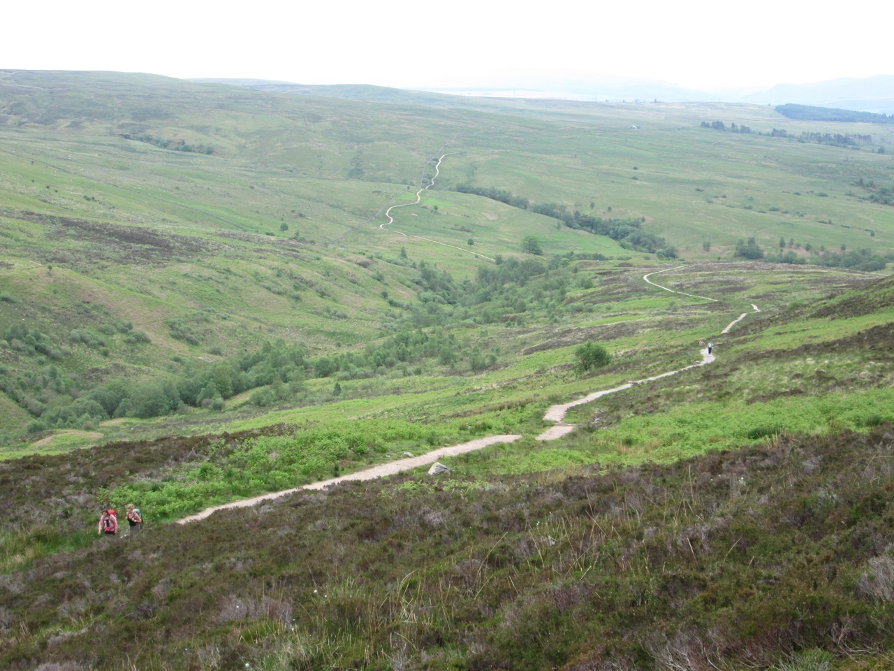 Walkers on the path up Conic Hill, looking back along the winding hillside route.