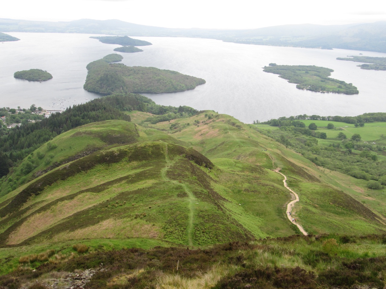 Open hillside path descending toward Loch Lomond and its islands from Conic Hill.